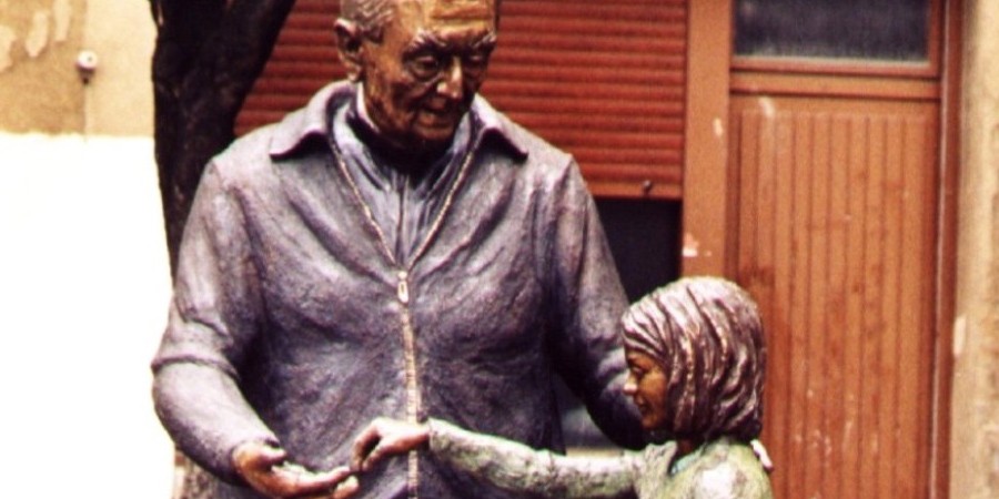 Escultura en bronce de la imagen del párroco de Ermua D. Teodoro ofreciendo caramelos auna niña.